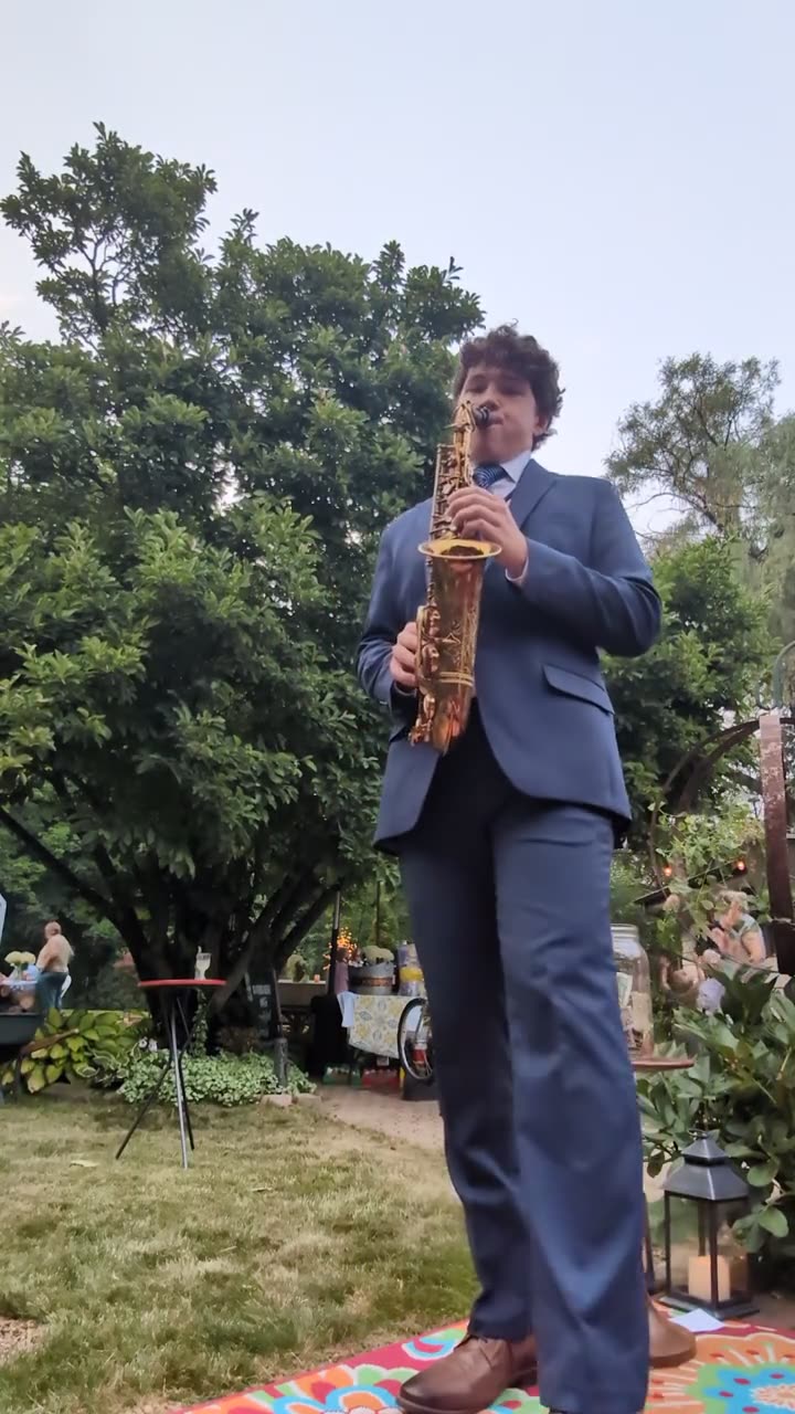 Liam Jakubowski playing saxophone at a garden celebration